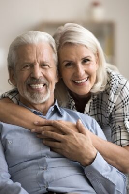 Smiling older couple with natural-looking teeth at home in Temecula
