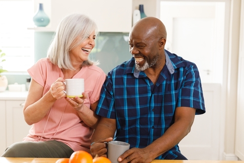 Happy senior couple laughing over coffee in their kitchen