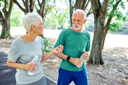 Active older couple smiling together on a walk in the park