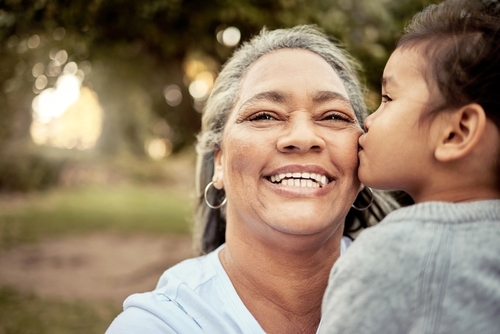 Smiling grandmother with healthy teeth enjoying time with her grandchild outdoors